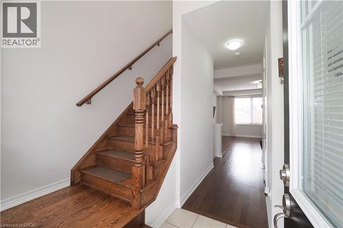 Entryway with wood-finish flooring extending into the main living areas, featuring a wood staircase with balusters and a handrail - 213 Seabrook Drive, Kitchener, ON 