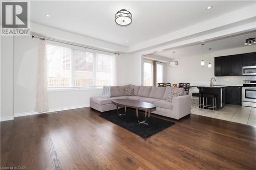 Spacious open-concept living area featuring rich wood-finish flooring, recessed lighting, and a large window - 213 Seabrook Drive, Kitchener, ON 