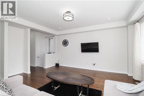 Open living space featuring wood-finish flooring, recessed lighting, a modern ceiling light fixture, and white painted walls - 213 Seabrook Drive, Kitchener, ON 
