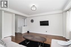 Open living space featuring wood-finish flooring, recessed lighting, a modern ceiling light fixture, and white painted walls - 