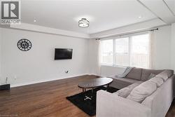 Living area featuring wood-finish flooring, recessed ceiling lighting, a contemporary ceiling fixture, and a large window with blinds - 