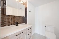 Bathroom vanity featuring a light wood-finish cabinet with black hardware, a pristine white countertop, and an integrated rectangular sink - 