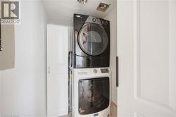 Dedicated laundry area featuring a stacked washer and dryer unit, overhead ventilation, and a white paneled door - 