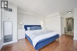 Bright bedroom featuring wood-finish flooring, white walls, and a built-in closet with sliding doors - 