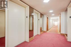 Corridor featuring elevator access, recessed lighting, wood trim, and a patterned runner over broadloom carpeting - 