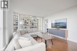 Living area featuring expansive floor-to-ceiling windows, wood-finish flooring, and white painted walls - 