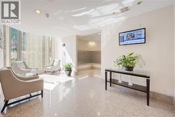 Brightly lit common area featuring expansive windows with vertical blinds, recessed lighting, and a wall-mounted television - 