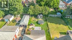 Expansive property featuring a detached garage, shaded patio structure, wooden privacy fencing, and mature trees - 
