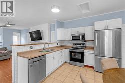 Kitchen featuring white cabinetry, stainless steel appliances, ceramic tile flooring, and a subway tile backsplash - 
