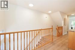 Light wood-finish flooring extending from a landing with a natural wood railing - 