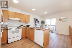 Kitchen featuring wood cabinetry, white subway tile backsplash, white appliances, and wood-finish flooring - 