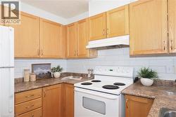 Kitchen featuring wood-finish cabinetry, white subway tile backsplash, laminate countertops, and a white electric range with matching range hood - 