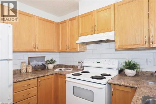 Kitchen featuring wood-finish cabinetry, white subway tile backsplash, laminate countertops, and a white electric range with matching range hood - 619 Wild Ginger Avenue Unit# H47, Waterloo, ON - Indoor Photo Showing Kitchen