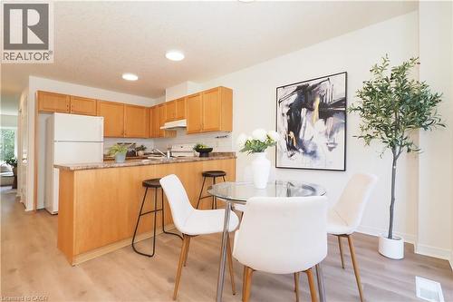 Open-concept kitchen and dining area featuring wood-finish flooring, recessed lighting, light wood cabinetry, and a peninsula with countertop seating - 619 Wild Ginger Avenue Unit# H47, Waterloo, ON - Indoor