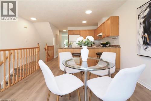 Open-concept living area featuring wood-finish flooring, recessed lighting, and a light-toned kitchen with wood cabinetry and a breakfast bar - 619 Wild Ginger Avenue Unit# H47, Waterloo, ON - Indoor Photo Showing Dining Room