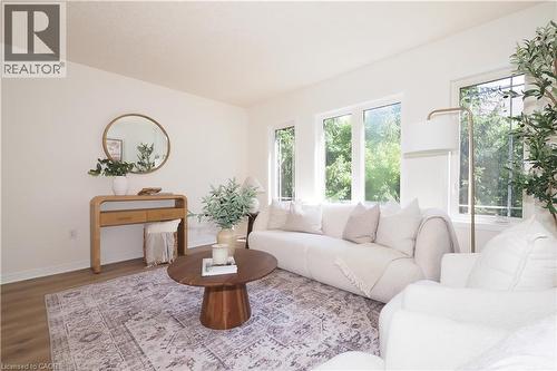 Bright interior space featuring white walls, wood-finish flooring, and multiple large windows - 619 Wild Ginger Avenue Unit# H47, Waterloo, ON - Indoor Photo Showing Living Room