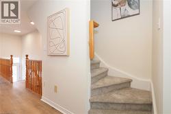 Carpeted staircase with wood handrail, light wood-finish flooring, and recessed ceiling lights - 
