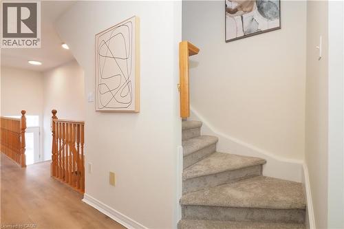 Carpeted staircase with wood handrail, light wood-finish flooring, and recessed ceiling lights - 619 Wild Ginger Avenue Unit# H47, Waterloo, ON - Indoor Photo Showing Other Room