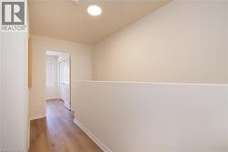 Hallway with wood-finish flooring, white baseboards, and a flush-mount ceiling light - 