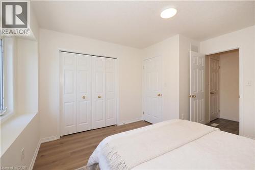 Bedroom featuring light wood-finish flooring, white walls, and a large bi-fold closet - 619 Wild Ginger Avenue Unit# H47, Waterloo, ON - Indoor Photo Showing Bedroom