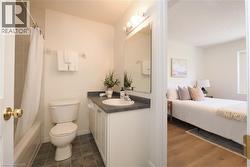 Bathroom featuring a white vanity with a dark countertop, an integrated sink, and a mirrored medicine cabinet with overhead lighting - 