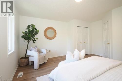 Spacious interior featuring wood-finish flooring, light-colored walls, a window with white trim, a six-panel door, and a bi-fold closet door - 619 Wild Ginger Avenue Unit# H47, Waterloo, ON - Indoor Photo Showing Bedroom
