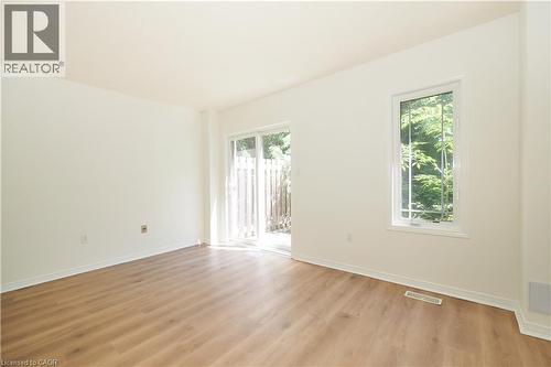 Spacious room featuring wood-finish flooring, white baseboards, and neutral wall tones - 619 Wild Ginger Avenue Unit# H47, Waterloo, ON - Indoor Photo Showing Other Room