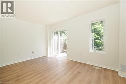 Spacious room featuring wood-finish flooring, white baseboards, and neutral wall tones - 