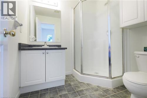 Bathroom featuring a corner shower with frosted glass enclosure, white vanity with dark countertop, and a built-in toilet - 619 Wild Ginger Avenue Unit# H47, Waterloo, ON - Indoor Photo Showing Bathroom