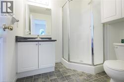 Bathroom featuring a corner shower with frosted glass enclosure, white vanity with dark countertop, and a built-in toilet - 