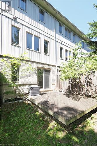 Exterior multi-level residence featuring a wood deck, stone base, vertical siding, and multiple windows - 619 Wild Ginger Avenue Unit# H47, Waterloo, ON - Outdoor