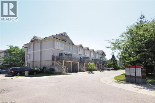 Multi-level townhouse-style units featuring light-colored siding, dark roofing, and individual balconies - 619 Wild Ginger Avenue Unit# H47, Waterloo, ON - Outdoor