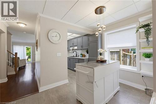 Kitchen area featuring gray cabinetry, a white movable island, a window with a cellular shade, and built-in shelving - 520 Mayflower Street, Waterloo, ON - Indoor
