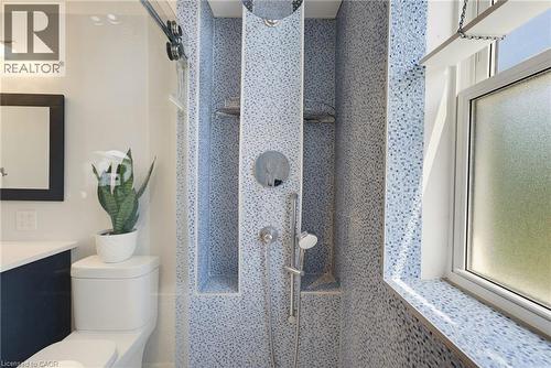 Shower enclosure featuring light blue mosaic tile, a ceiling-mounted rainfall showerhead, and a handheld shower unit - 520 Mayflower Street, Waterloo, ON - Indoor Photo Showing Bathroom