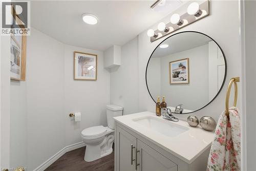 Contemporary bathroom featuring a modern vanity with integrated sink, a large circular mirror, and a five-light vanity fixture - 520 Mayflower Street, Waterloo, ON - Indoor Photo Showing Bathroom