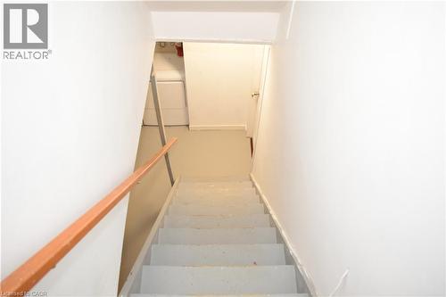 Staircase featuring a wood handrail, painted treads, and white wall finishes - 249 Cedarbrae Avenue Unit# 1, Waterloo, ON 