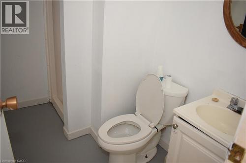 White toilet with an open lid, a white vanity with an integrated sink, and a chrome faucet - 249 Cedarbrae Avenue Unit# 1, Waterloo, ON 