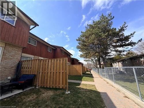 Private outdoor patio area with a wooden privacy fence, brick exterior, and red siding - 249 Cedarbrae Avenue Unit# 1, Waterloo, ON 