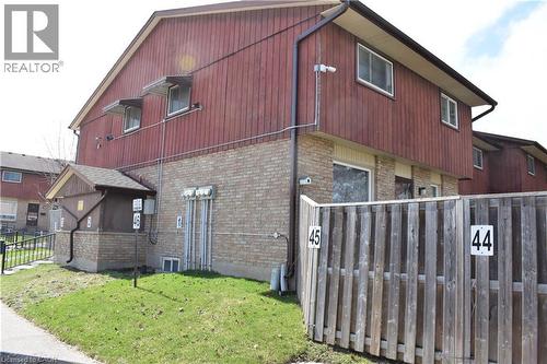 Exterior featuring a combination of brick and vertical wood siding, multiple windows with awning-style covers, a gabled roofline, and a privacy fence - 249 Cedarbrae Avenue Unit# 1, Waterloo, ON 