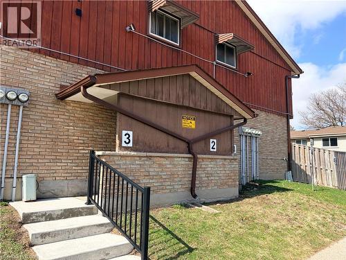 Brick and vertical wood siding exterior featuring a concrete staircase with a black metal handrail - 249 Cedarbrae Avenue Unit# 1, Waterloo, ON 