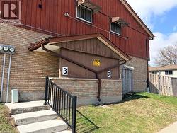 Brick and vertical wood siding exterior featuring a concrete staircase with a black metal handrail - 