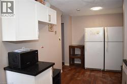 Kitchen area featuring white cabinetry with brushed nickel hardware, dark speckled countertops, and wood-finish flooring - 