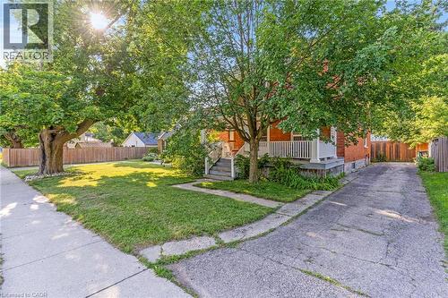 Traditional brick exterior featuring a covered front porch with white railings, a concrete walkway, and a paved driveway - 630 Lawrence Street, Cambridge, ON - Outdoor