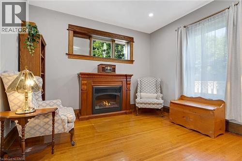 Electric fireplace with carved wood mantel, wood-finish flooring, light grey wall paint, and natural wood trim accents - 630 Lawrence Street, Cambridge, ON - Indoor With Fireplace