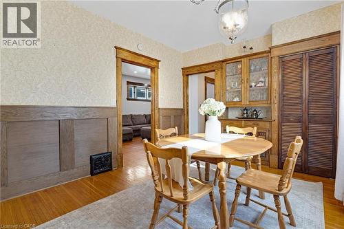 Dining area featuring wood-finish flooring, wainscoting, and a built-in wooden hutch with glass-front cabinetry - 630 Lawrence Street, Cambridge, ON - Indoor Photo Showing Dining Room