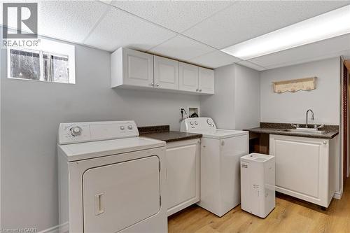 Dedicated laundry area featuring a washer and dryer, sink with chrome faucet, light wood-finish flooring, white cabinetry, and a window - 630 Lawrence Street, Cambridge, ON - Indoor Photo Showing Laundry Room