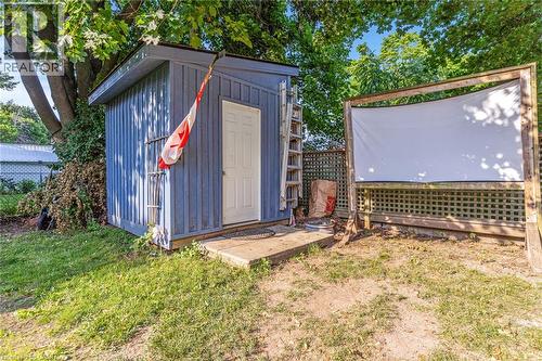 Freestanding shed with a white entry door, wood-paneled siding, and an adjacent wood-framed screen structure - 630 Lawrence Street, Cambridge, ON - Outdoor