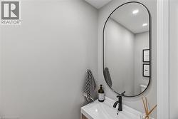 Modern bathroom vanity featuring a rectangular undermount sink, matte black faucet, and oval-framed mirror - 