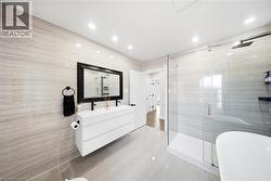 Bathroom featuring tile walls, vanity, a stall shower, light tile patterned floors, and a freestanding bath - 