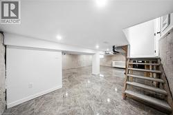 Finished basement featuring stairs and light marble finish flooring - 